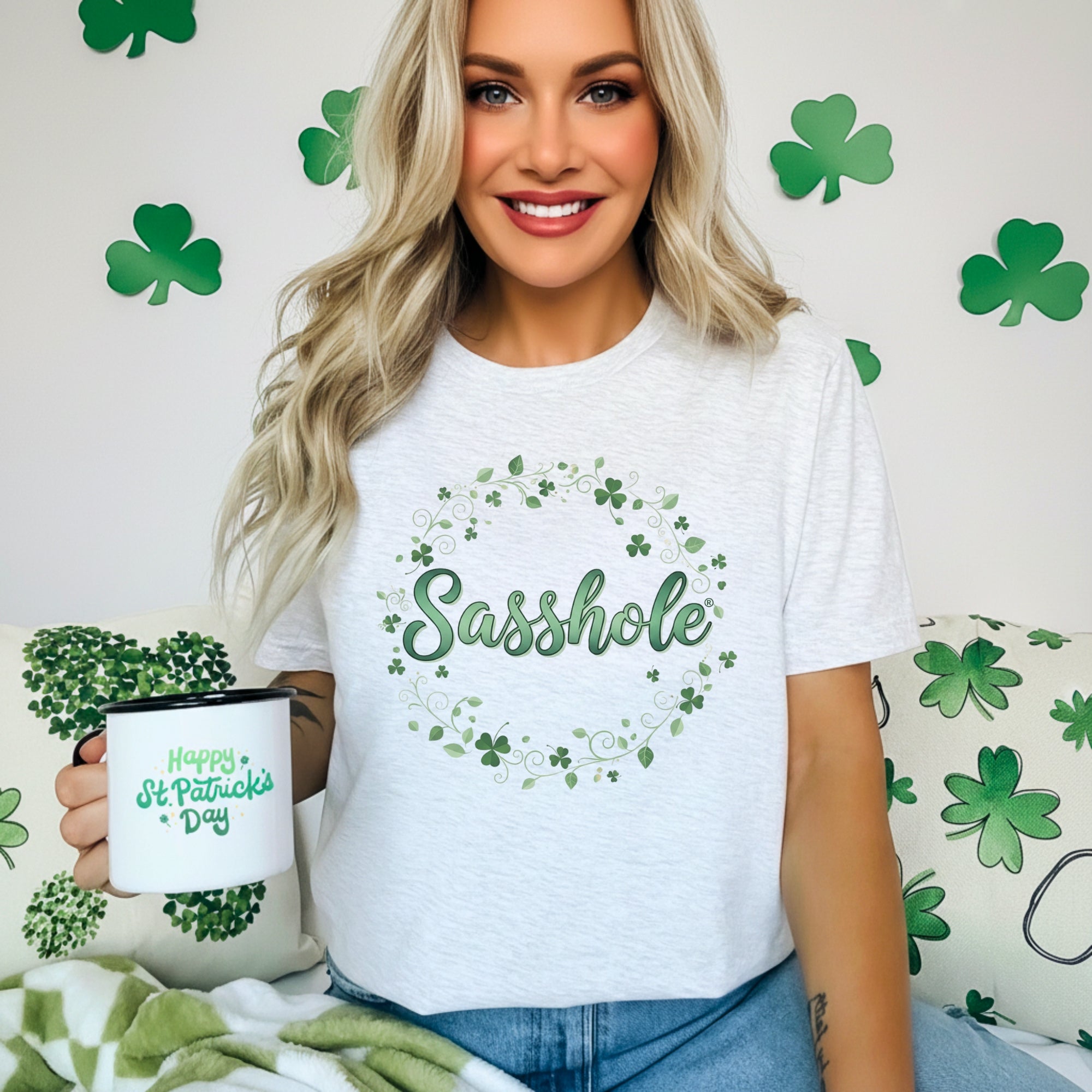 Image of Woman wearing a white t-shirt with 'Sasshole' and shamrock design, holding a mug with St. Patrick's Day design.