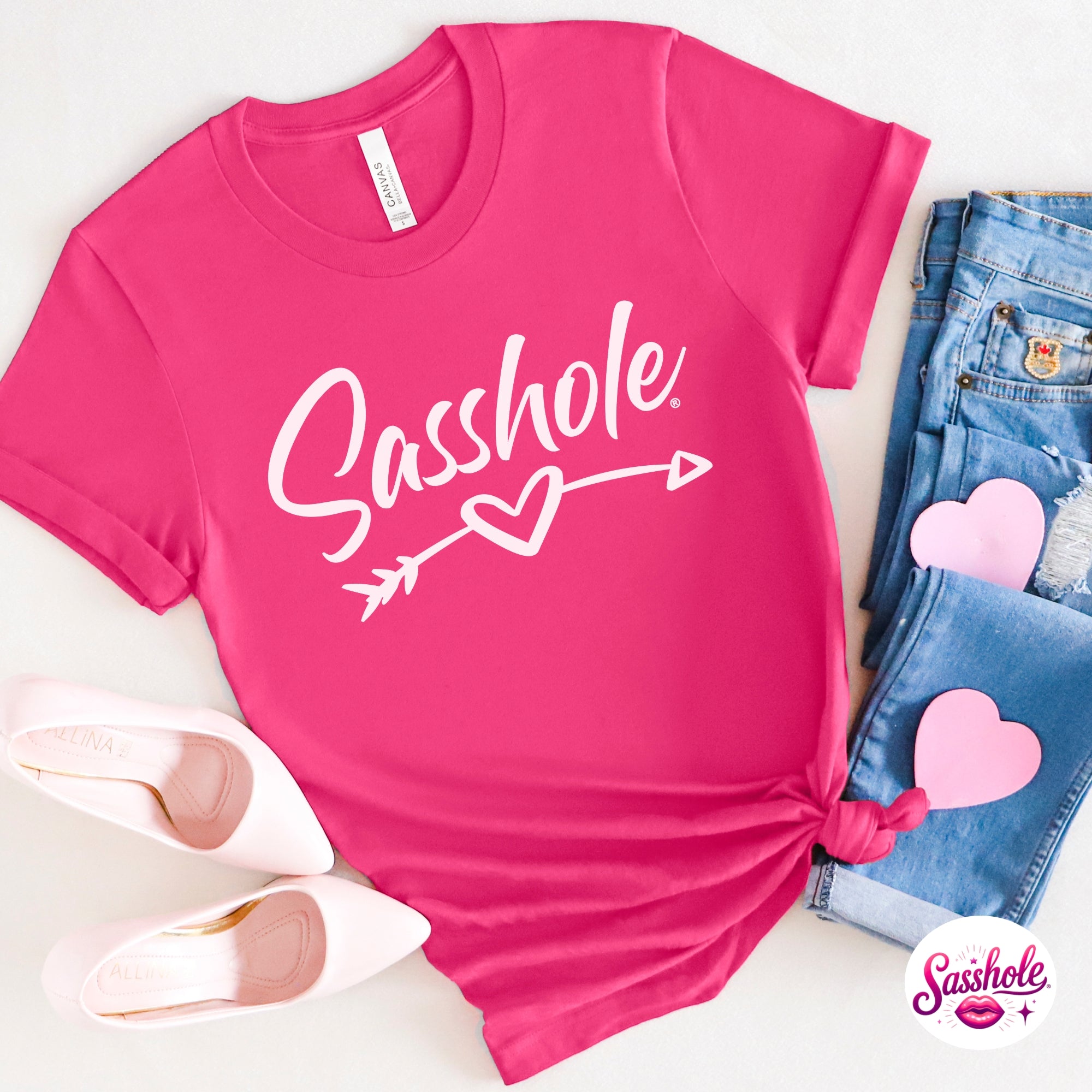 Pink t-shirt with 'Sashole' text and heart design, paired with jeans and shoes on a white background.