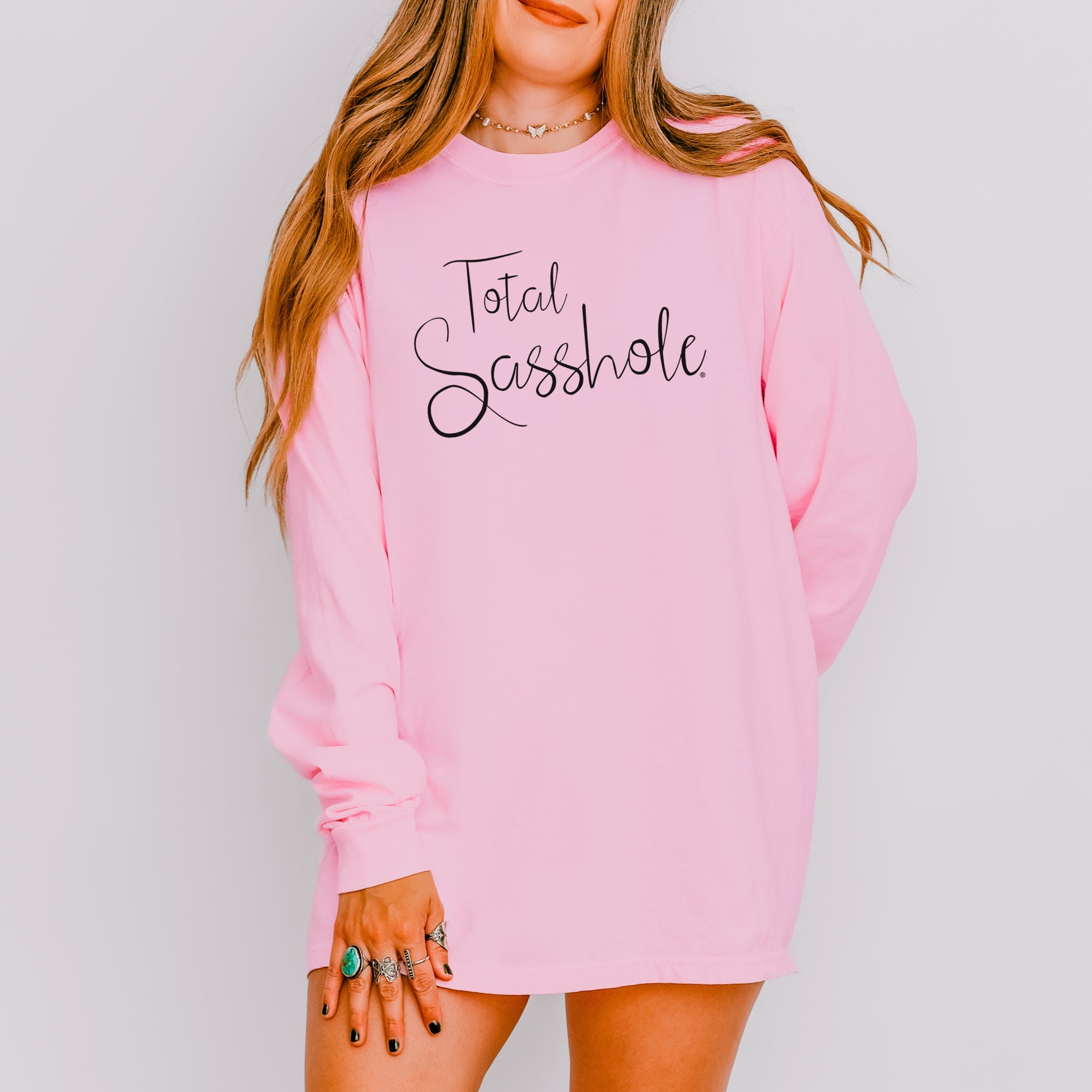 Image of Women wearing a pink long sleeve t-shirt with 'Total Sasshole' text on a gray background