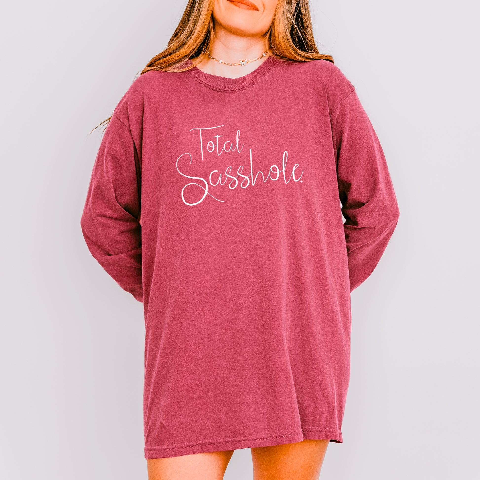 Woman wearing a brick long-sleeve shirt with 'Total Sasshole' text on a plain background