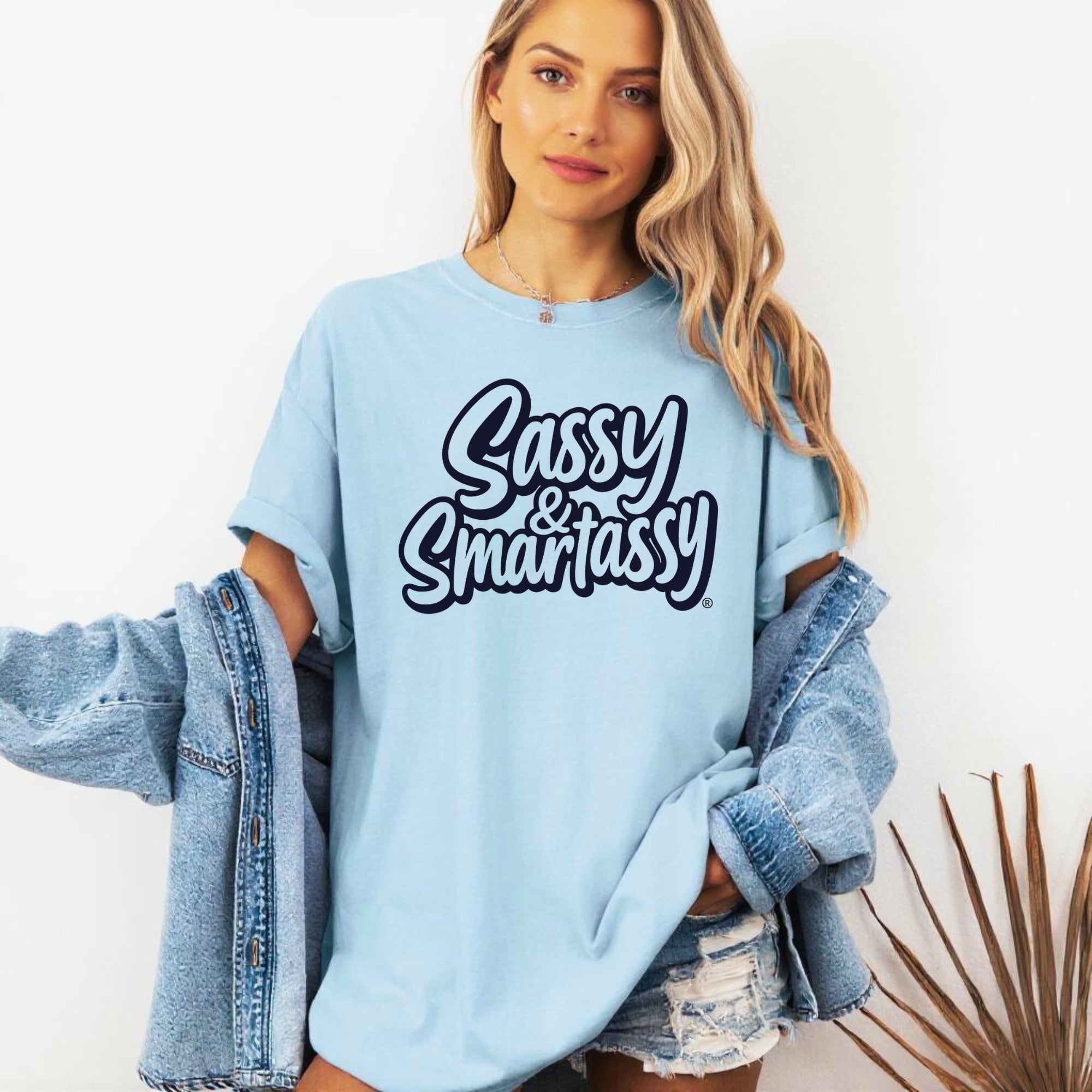 Image of Woman wearing a light blue sweatshirt with 'Sassy & Smartassy' text, holding a denim jacket.