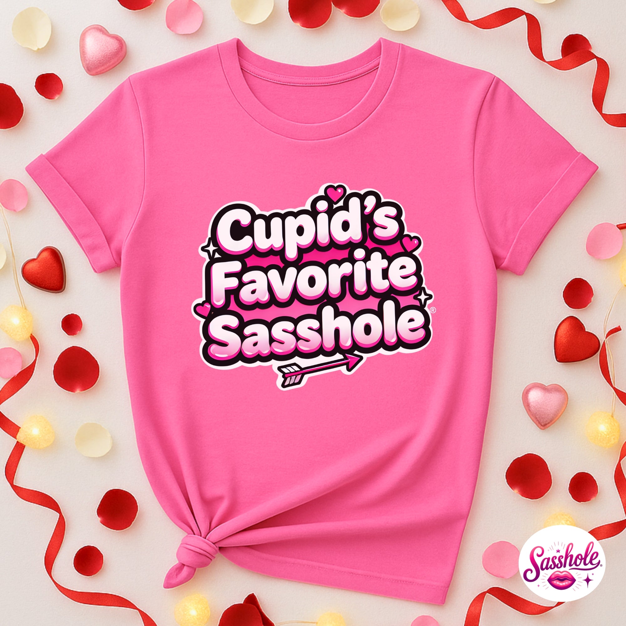 Pink t-shirt with 'Cupid's Favorite Sasshole' text on a decorative background with hearts and ribbons.