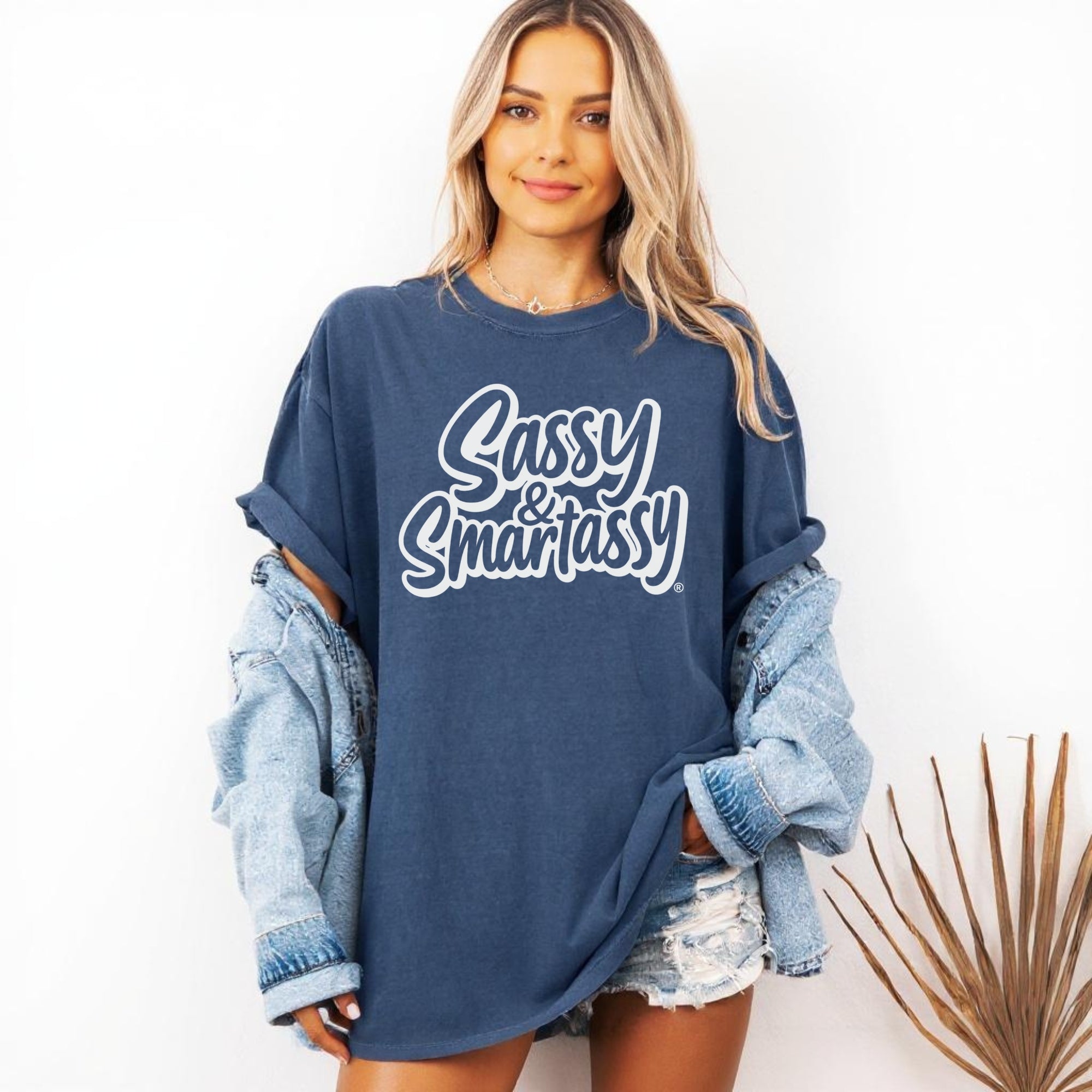 Woman wearing a navy blue oversized shirt with 'Sassy & Smartassy' text, holding a denim jacket.