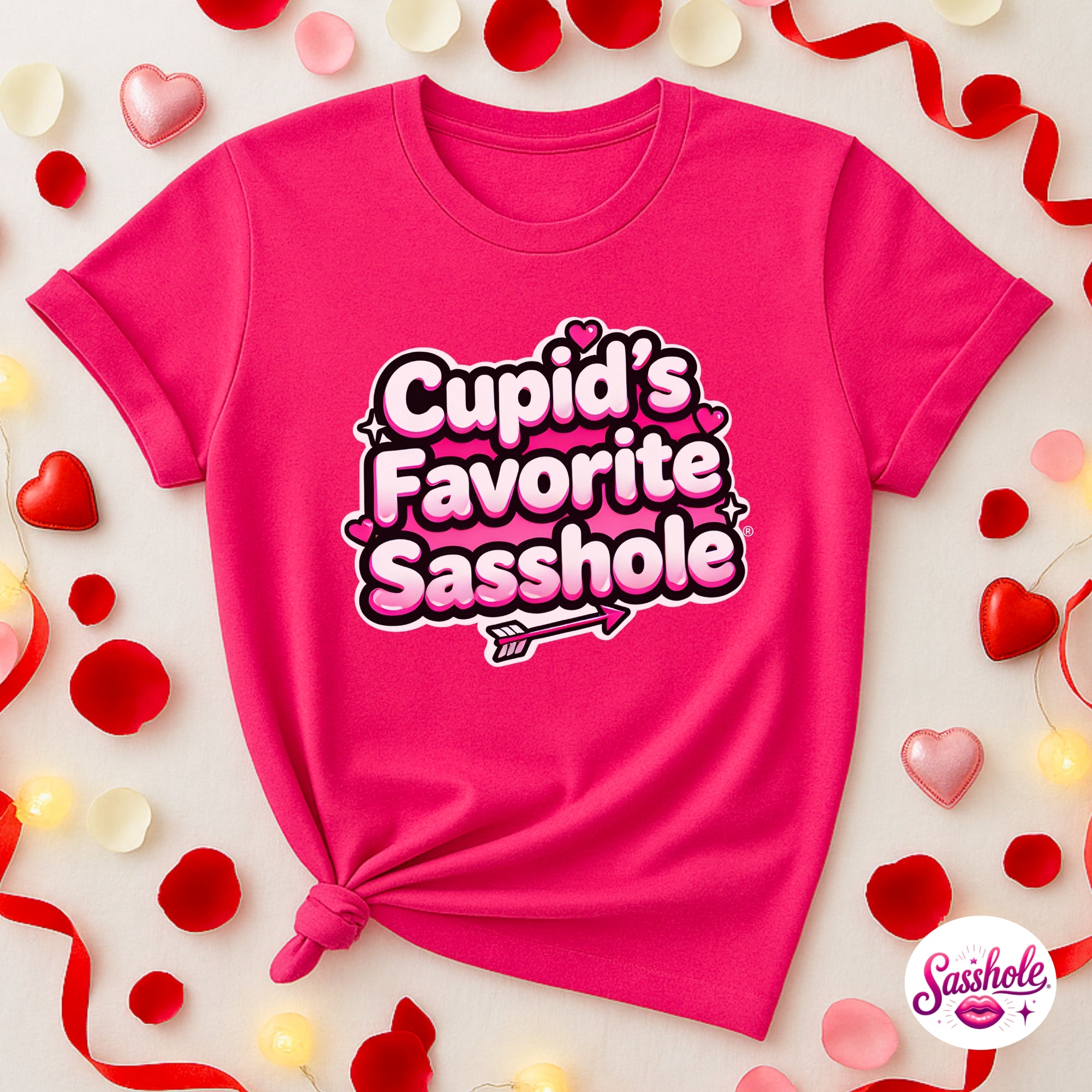 Pink t-shirt with 'Cupid's Favorite Sasshole' text on a decorative background with hearts and ribbons.