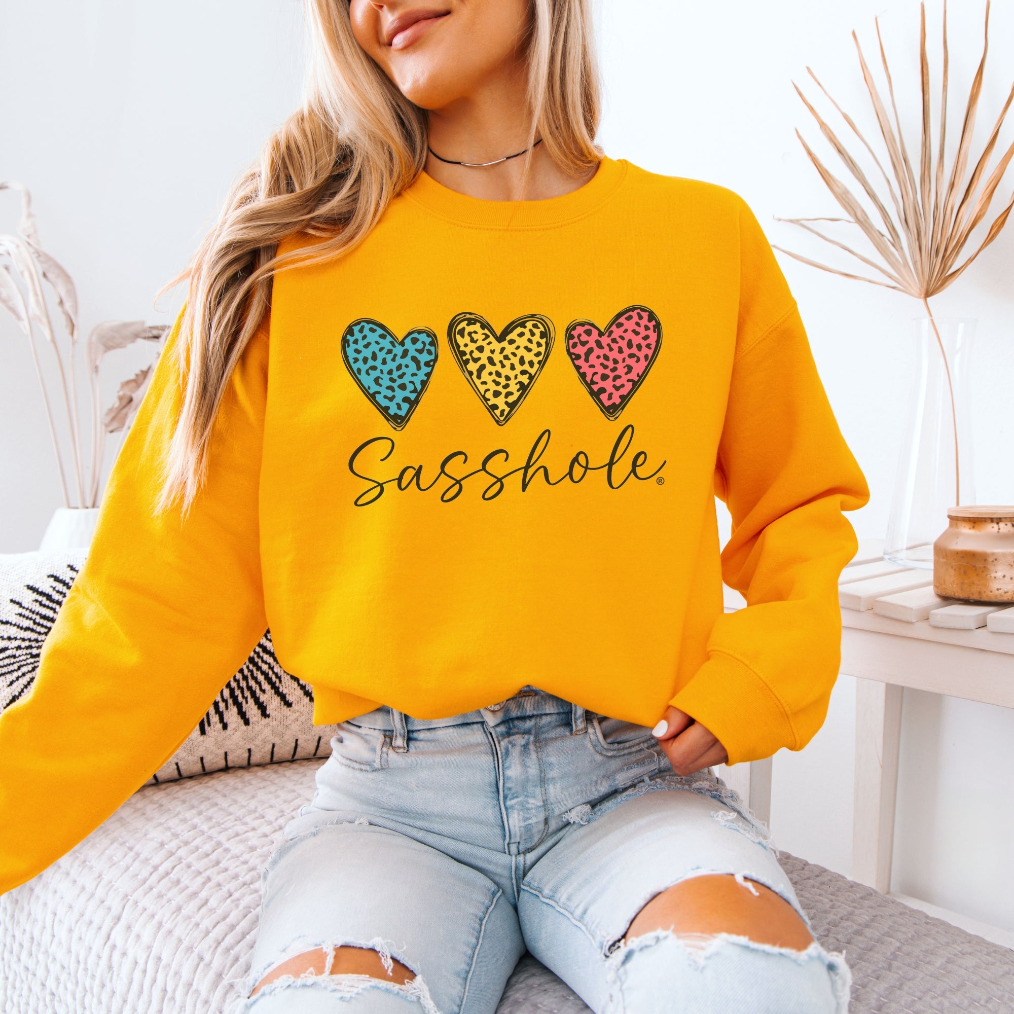 Image of Person wearing a yellow sweatshirt with colorful heart designs and text indoors.