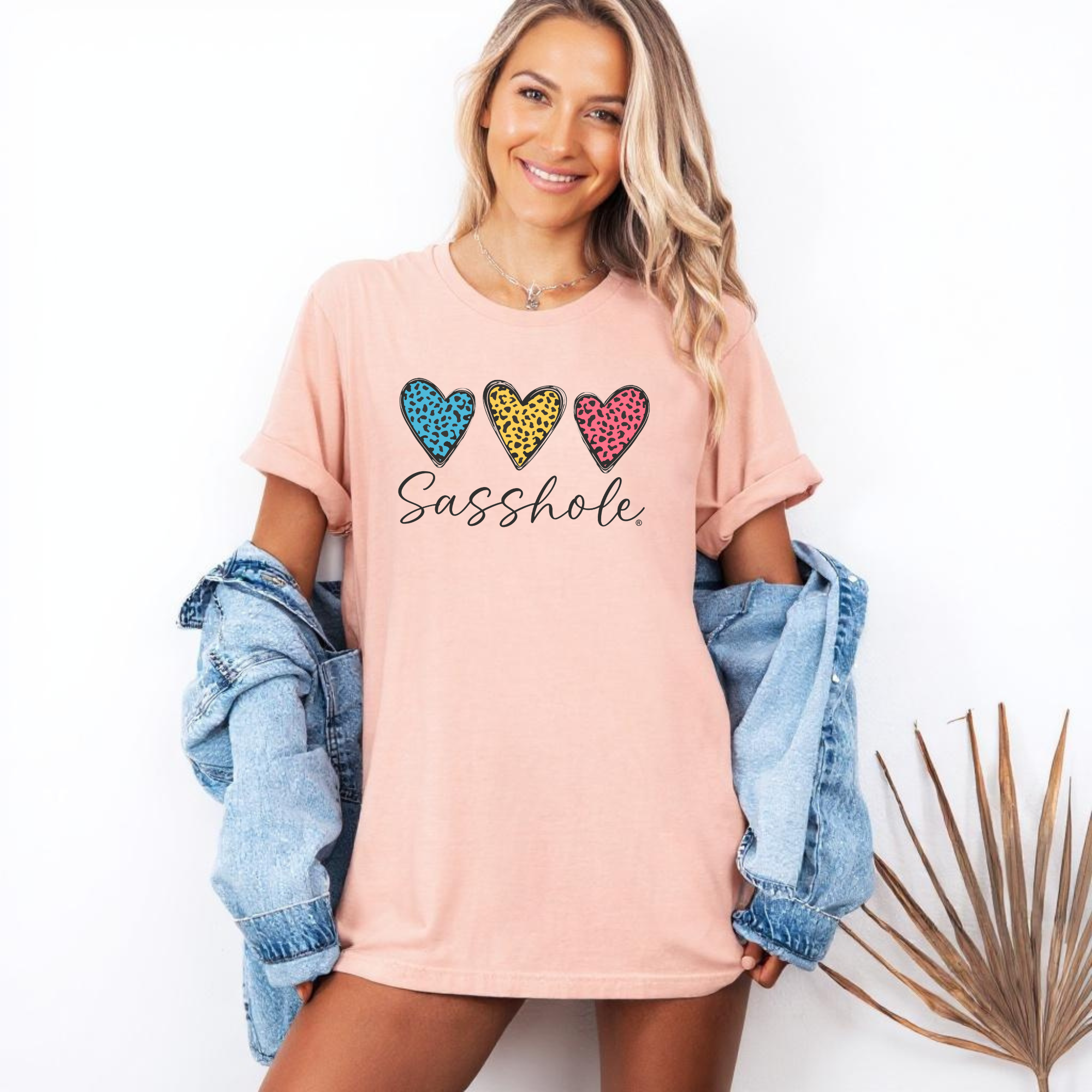 Image of Woman wearing a pink t-shirt with colorful heart designs and text, standing against a white background.