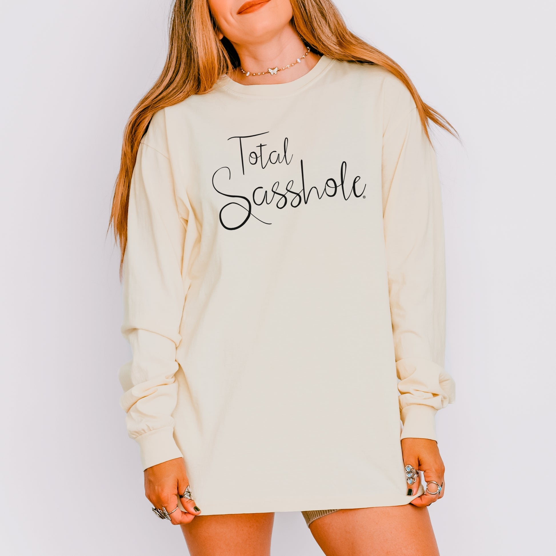 Woman wearing a ivory long sleeve t-shirt with 'Total Sasshole' text on a plain background