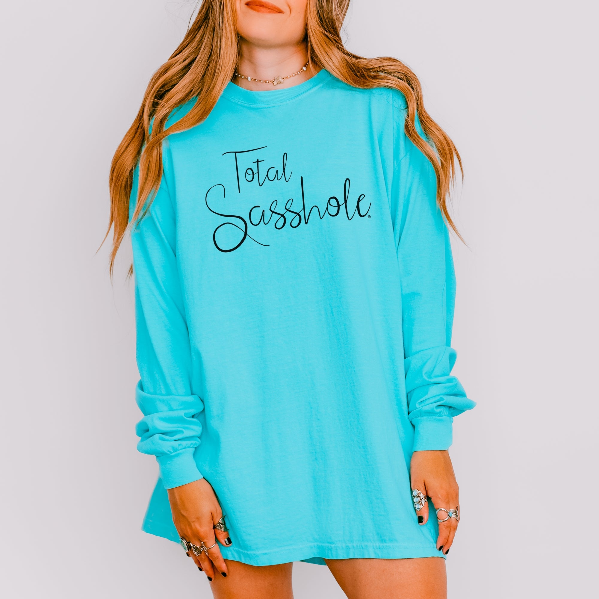 Image of Woman wearing a turquoise long-sleeve shirt with 'Total Sasshole' text on a plain background