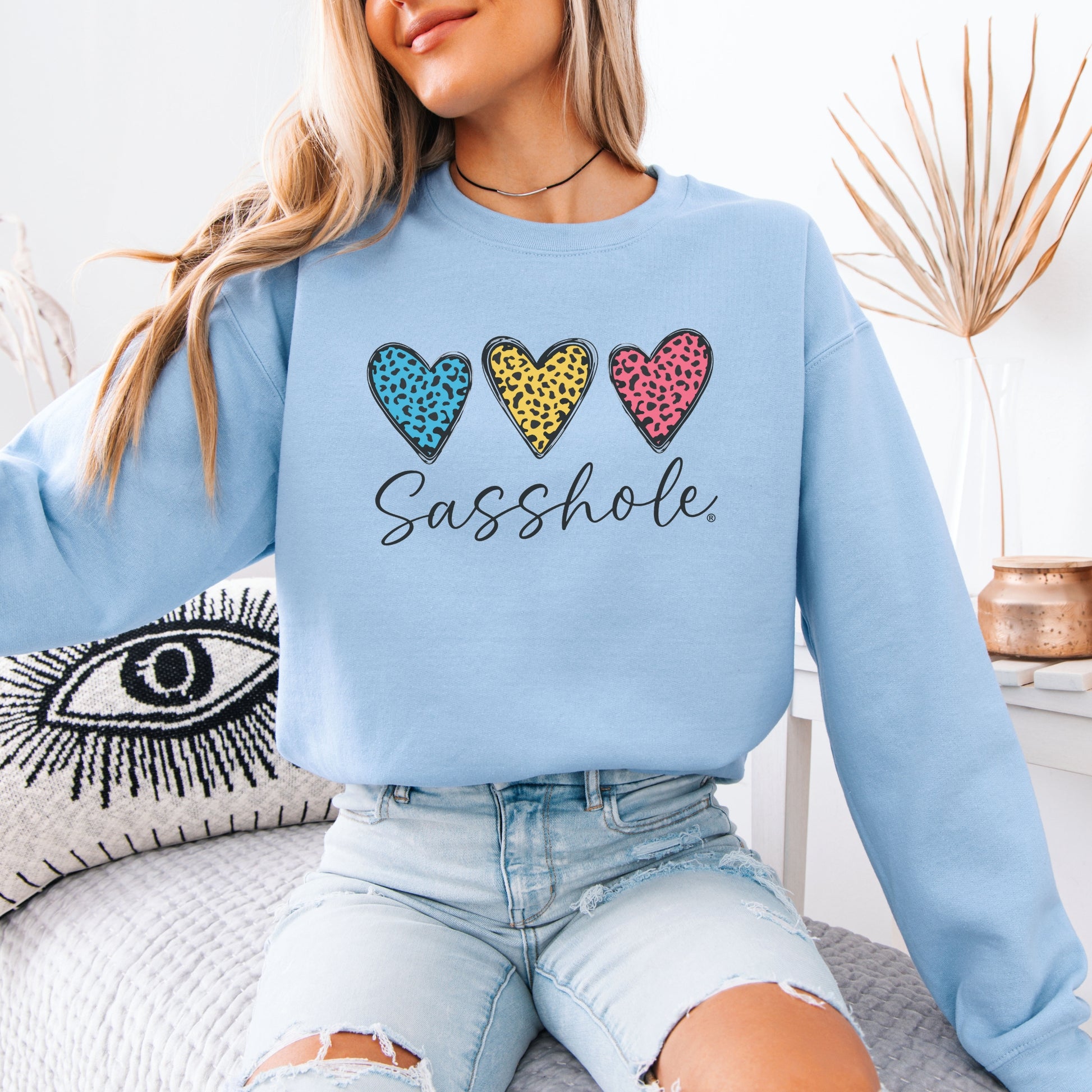 Person wearing a light blue sweatshirt with colorful heart designs and text.