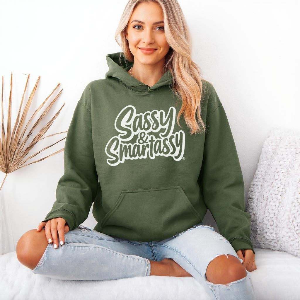 Image of Woman wearing a military green hoodie with 'Sassy & Smartassy' text, sitting on a white couch.