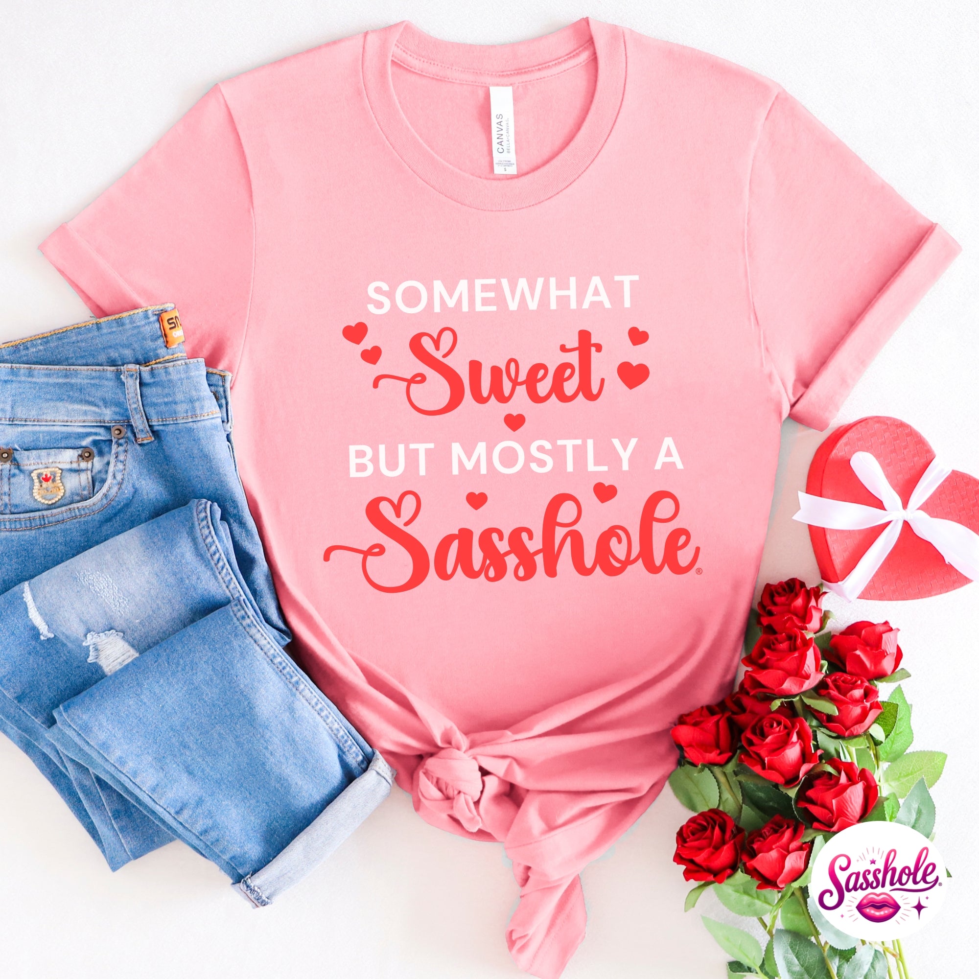 Image of Pink t-shirt with humorous text, blue jeans, and red roses on a white background
