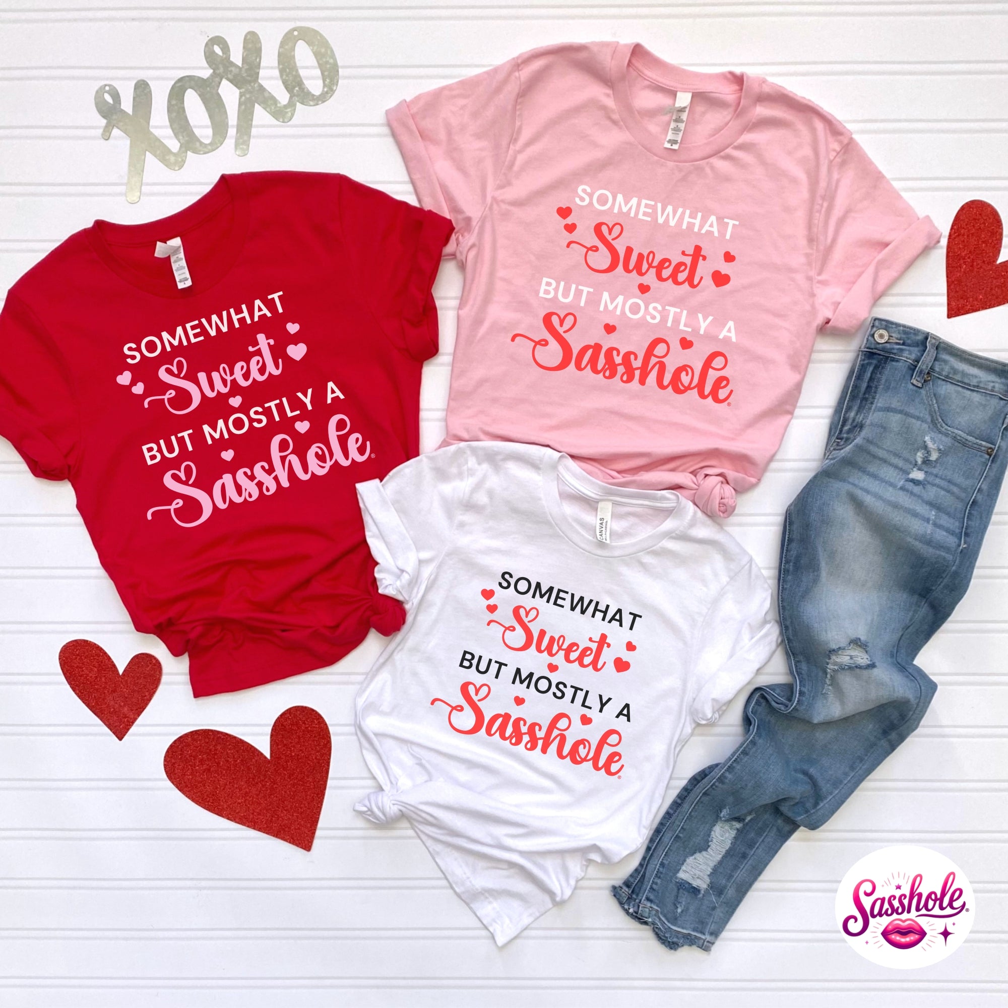 Three t-shirts with humorous text on a white background, surrounded by hearts and jeans.