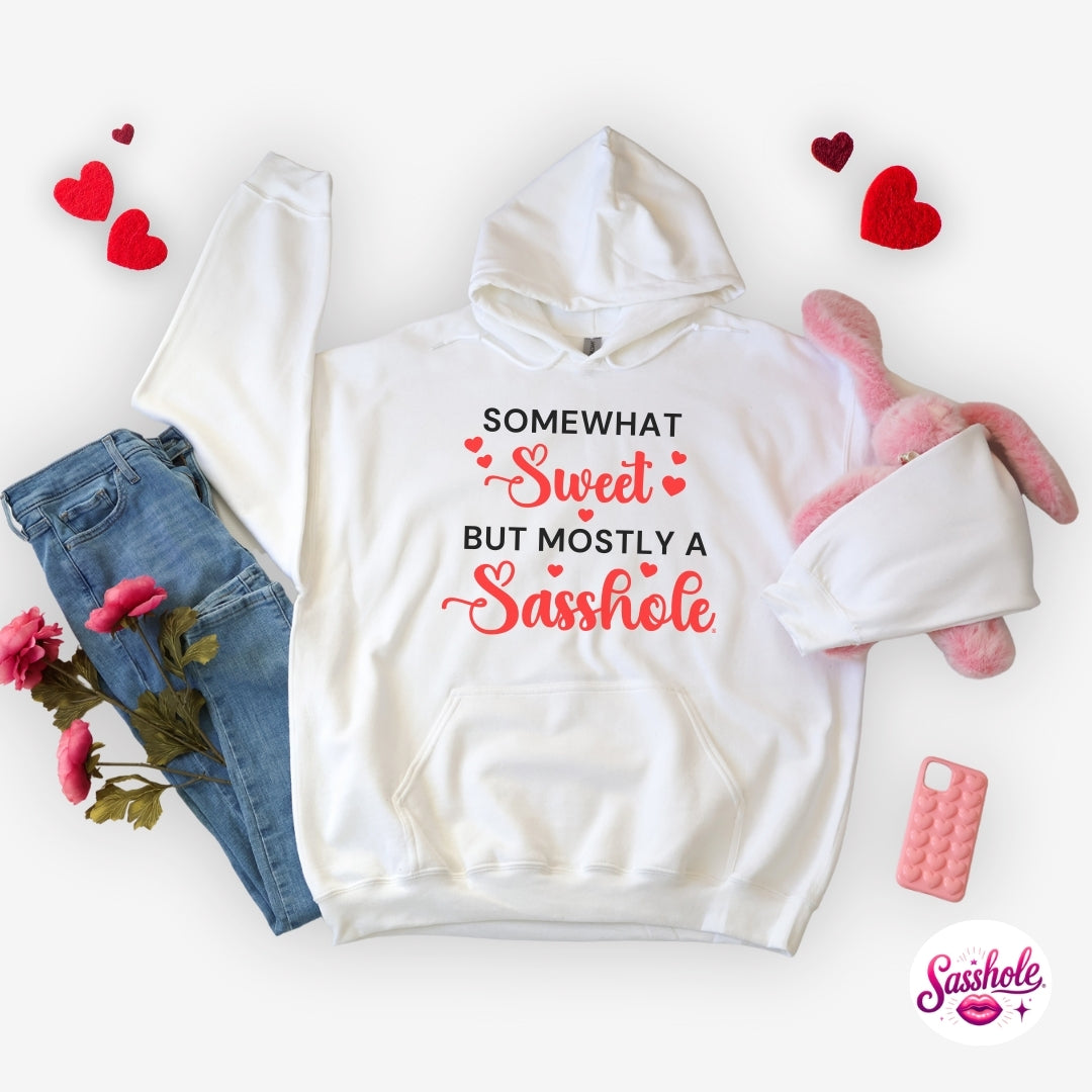 White hoodie with humorous text, paired with jeans, a teddy bear, and flowers on a white background.
