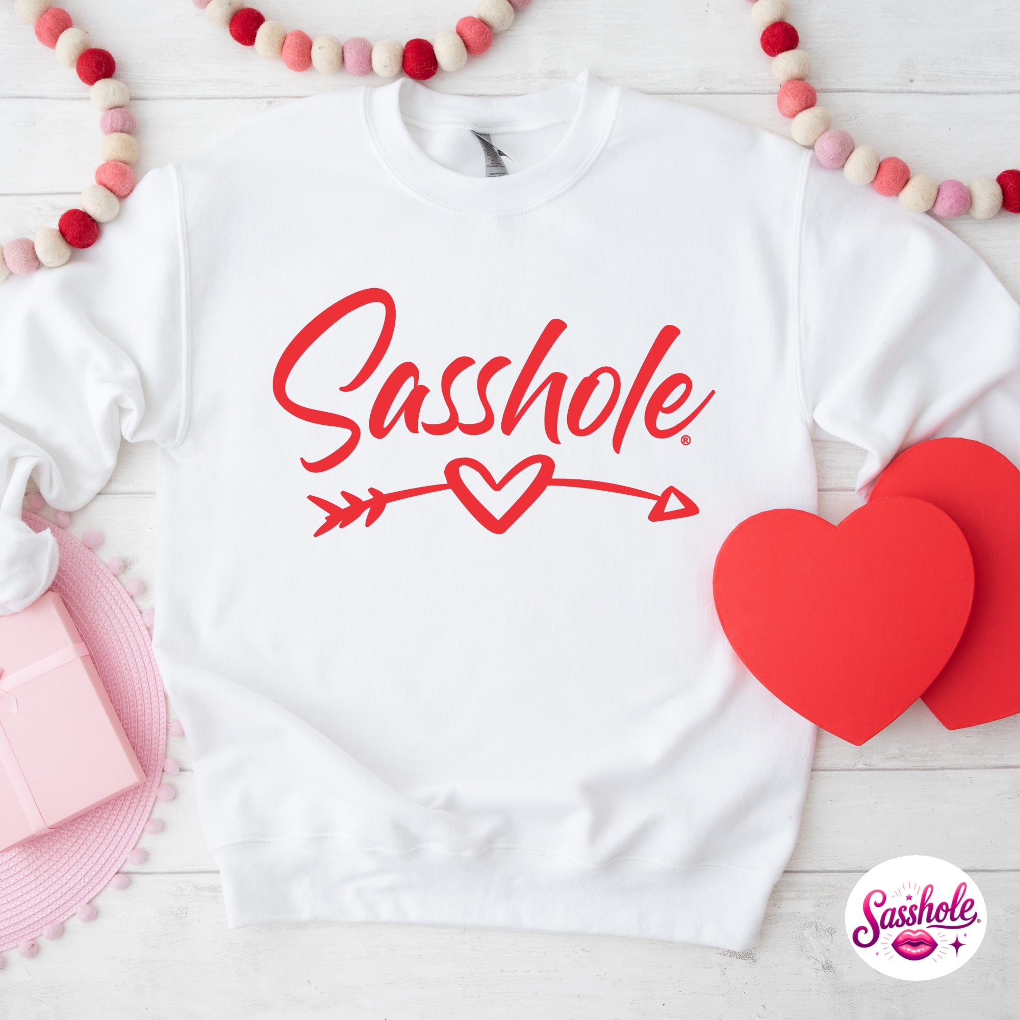 Image of White sweatshirt with 'Sasshole' text and red hearts on a white background