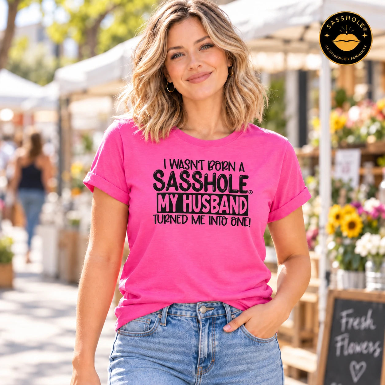 Image of I Wasn’t Born a Sasshole, My Husband Turned Me Into One! tee in Charity Pink, outdoor lifestyle view.