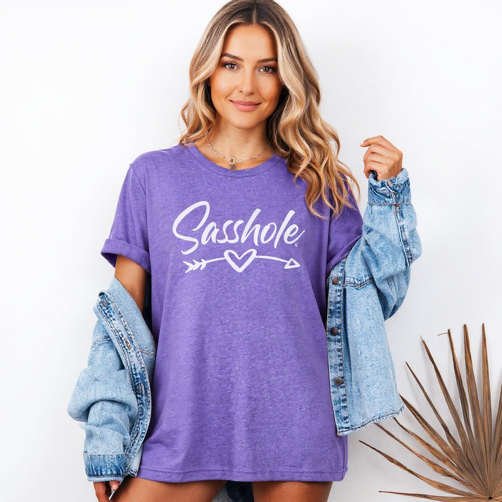 Woman wearing a purple t-shirt with 'Sasshole' text, holding a denim jacket on a white background.